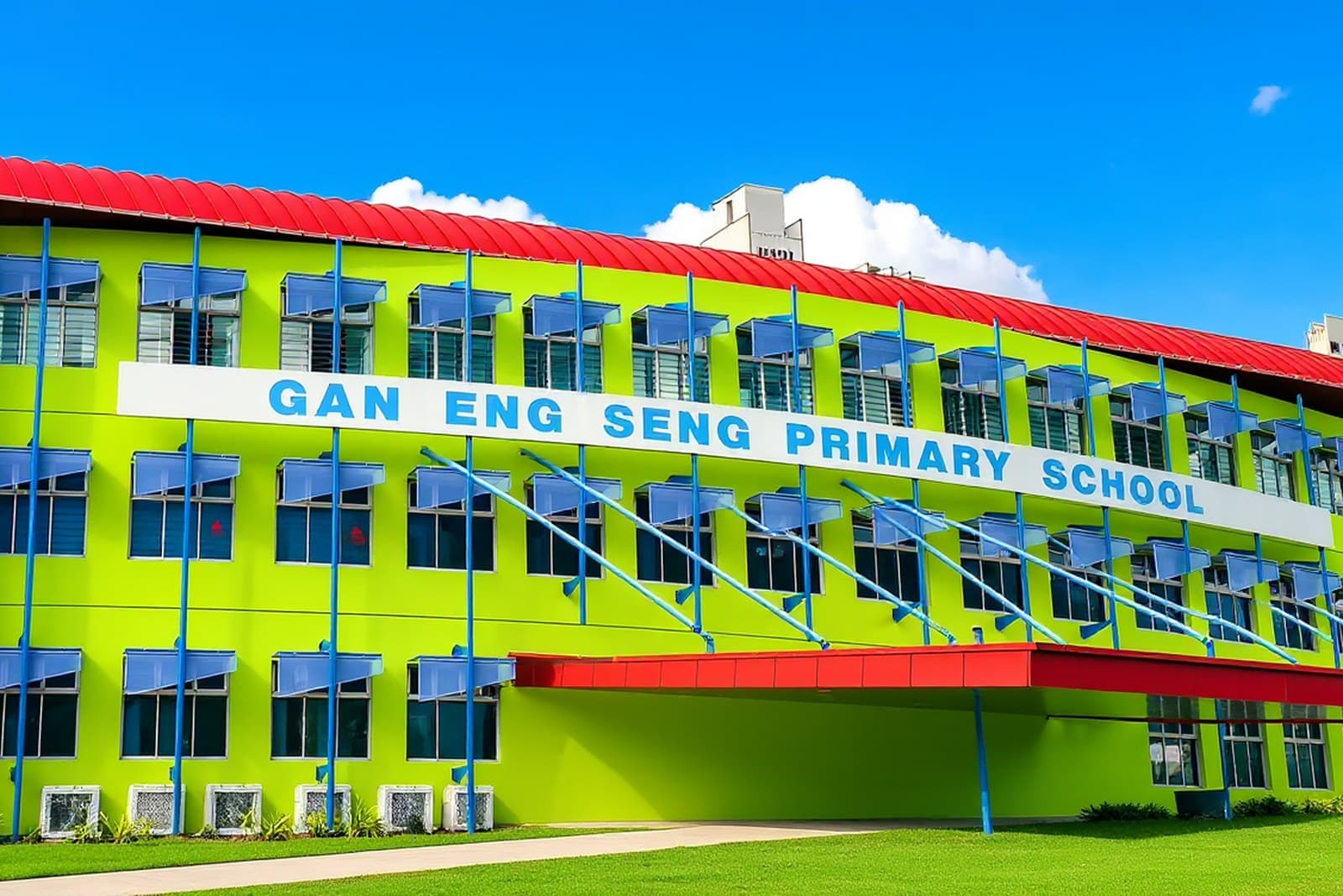 Gan Eng Seng Primary School, a lime green building with a red roof and blue window awnings, under a clear blue sky